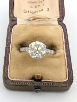 Bague en or blanc avec gros diamant central et diamants sur la tige
