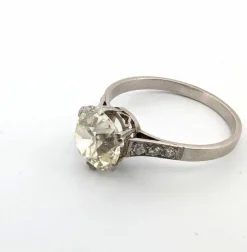 Bague en or blanc avec gros diamant central et diamants sur la tige