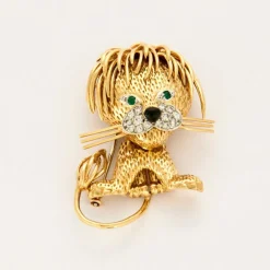 Broche Lion en or jaune et blanc, émeraudes, diamants et onyx