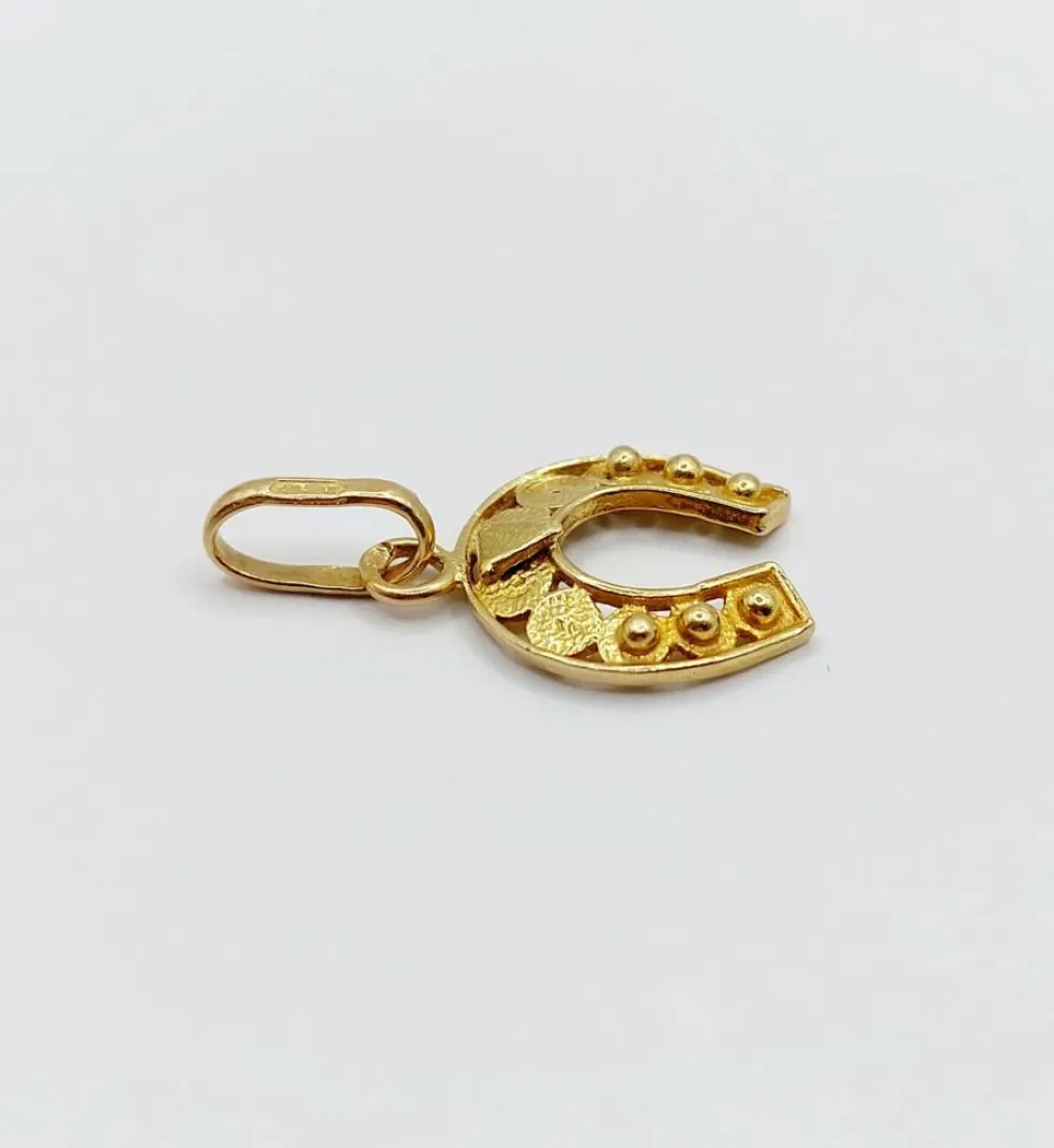 Pendentif vintage or jaune représentant un fer à cheval finement décoré
